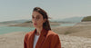 long haired woman wearing burnt orange coat and a white inner top moving in slow mo